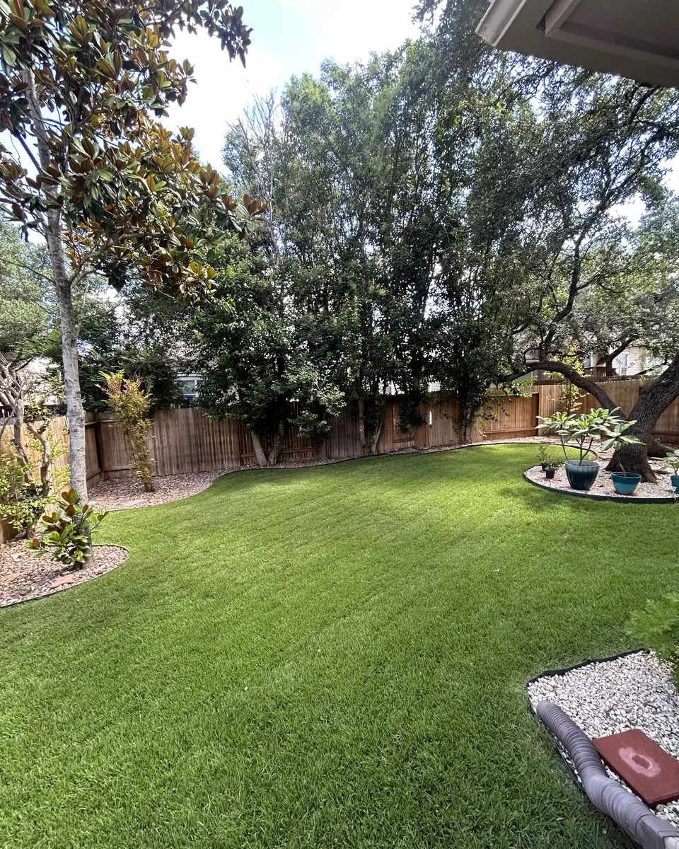 Backyard lawn freshly mowed by Rivera's Lawn Services, with clean edges along the mulch and rock beds